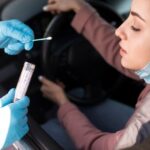 Person testing a woman in the car for coronavirus