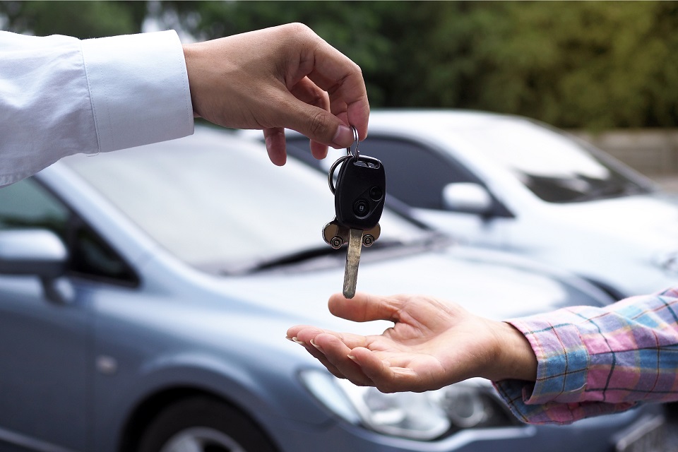 A picture of a car buyer getting their keys to their new car handed to them.